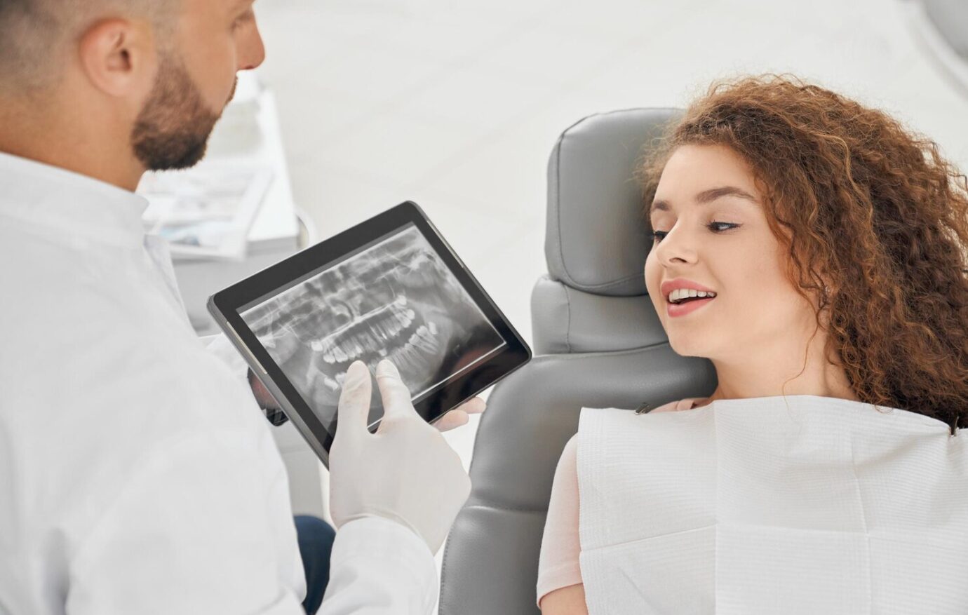 skilled-male-dentist-showing-x-ray-picture-teeth-woman_651396-1393